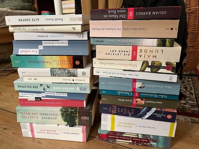 Beispielfoto für Buchspenden: Frontale Ansicht von Buchstapeln. Die einzelnen Titel auf den Buchrücken sind zu erkennen.